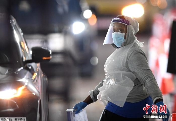 當(dāng)?shù)貢r間12月18日，英國政府公布的數(shù)據(jù)顯示，當(dāng)天英國新增奧密克戎毒株感染病例10059例。鑒于奧密克戎毒株感染病例激增，住院人數(shù)不斷上升，倫敦市長宣布倫敦進(jìn)入“重大事故”狀態(tài)。圖為倫敦的一個免下車檢測中心，一名醫(yī)務(wù)工作者正準(zhǔn)備對司機(jī)進(jìn)行核酸檢測。