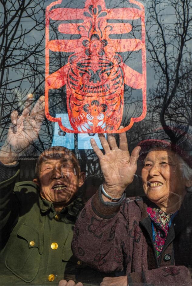 臘月里，霍州市師莊鄉(xiāng)馮南垣村村民師榮光(左)在災(zāi)后重建的新家里貼窗花。(霍州市委宣傳部供圖)