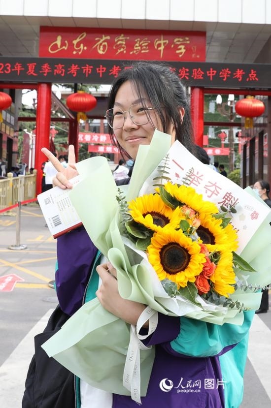 6月7日高考首日，山東67萬考生走進考場，拼搏逐夢。在山東省實驗中學(xué)考點，考生進考場前手捧向日葵花拍照留念，寓意“一舉奪魁”。人民網(wǎng)記者 劉祺攝