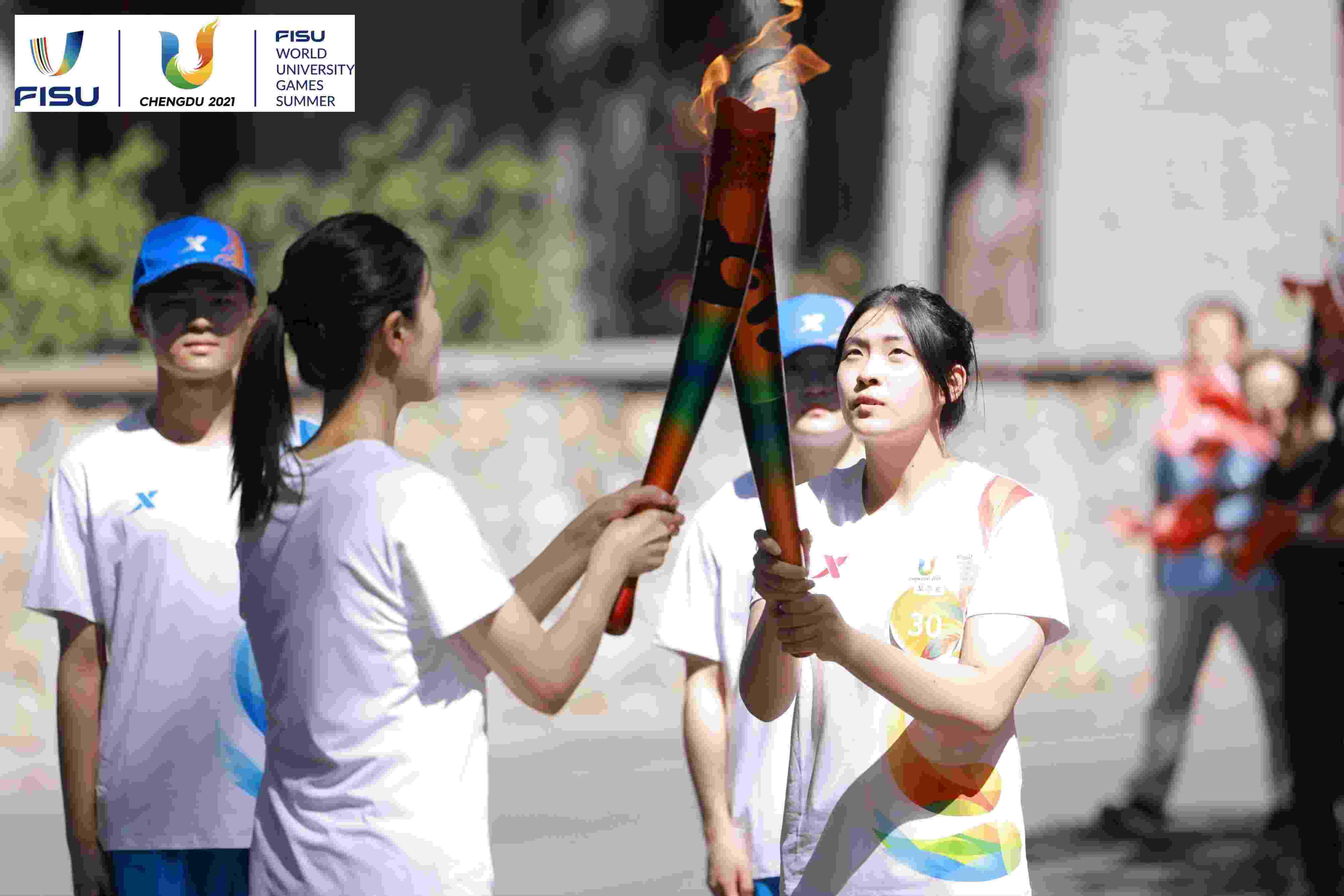 兩名大運(yùn)會火炬手進(jìn)行火炬?zhèn)鬟f。 圖片來源：成都大運(yùn)會執(zhí)委會供圖