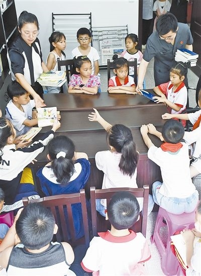  圖④：法院干警為留守兒童發(fā)放暑假讀物。