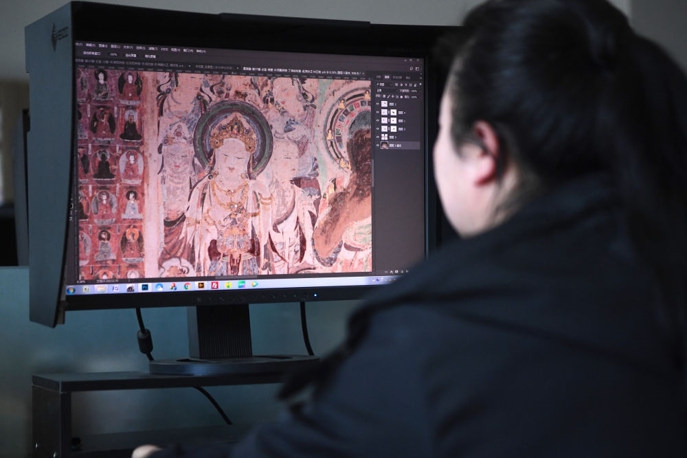 敦煌研究院文物數(shù)字化保護(hù)團(tuán)隊(duì)圖像處理人員年海麗在拼接壁畫圖像（2023年4月25日攝）。數(shù)字化探索為莫高窟的保護(hù)與傳承開辟了全新路徑，數(shù)字技術(shù)讓敦煌文物走出洞窟，跨出國門，走向“永久保存、永續(xù)利用”。新華社記者 陳斌 攝
