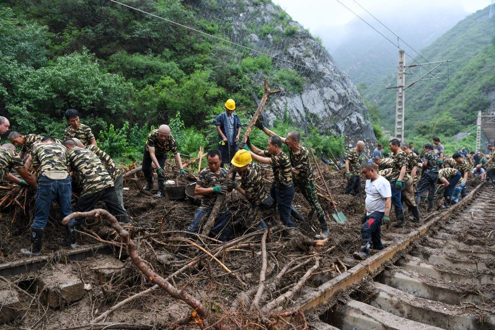 8月1日，在北京市門頭溝區(qū)水峪嘴村附近一段被阻斷的鐵路線上，中鐵六局工作人員在清理軌道上的雜物，全力恢復交通。新華社記者 鞠煥宗 攝