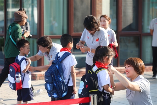 8月30日，雄安史家胡同小學學生體驗學校生活。老師為學生佩戴?；?。