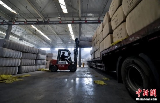 新疆喀什綜合保稅區(qū)，喀什啟路國際貿(mào)易有限公司的倉庫內(nèi)，工人正在裝載從塔吉克斯坦和烏茲別克斯坦進(jìn)口的棉花。劉新攝