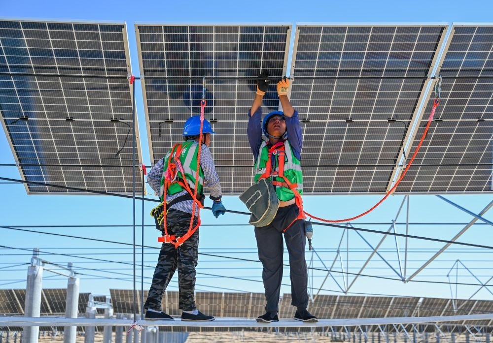 2023年7月22日，工人在位于內(nèi)蒙古杭錦旗庫(kù)布其沙漠億利生態(tài)示范區(qū)的蒙西基地庫(kù)布其200萬千瓦光伏治沙項(xiàng)目工地安裝光伏板。新華社記者 劉磊 攝