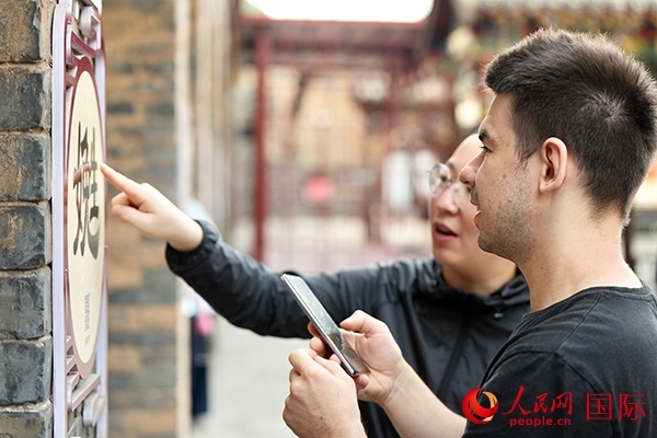 選手安德烈（俄羅斯）在老師指導(dǎo)下學(xué)習(xí)墻壁上張貼的生僻字。人民網(wǎng) 盧鵬宇攝