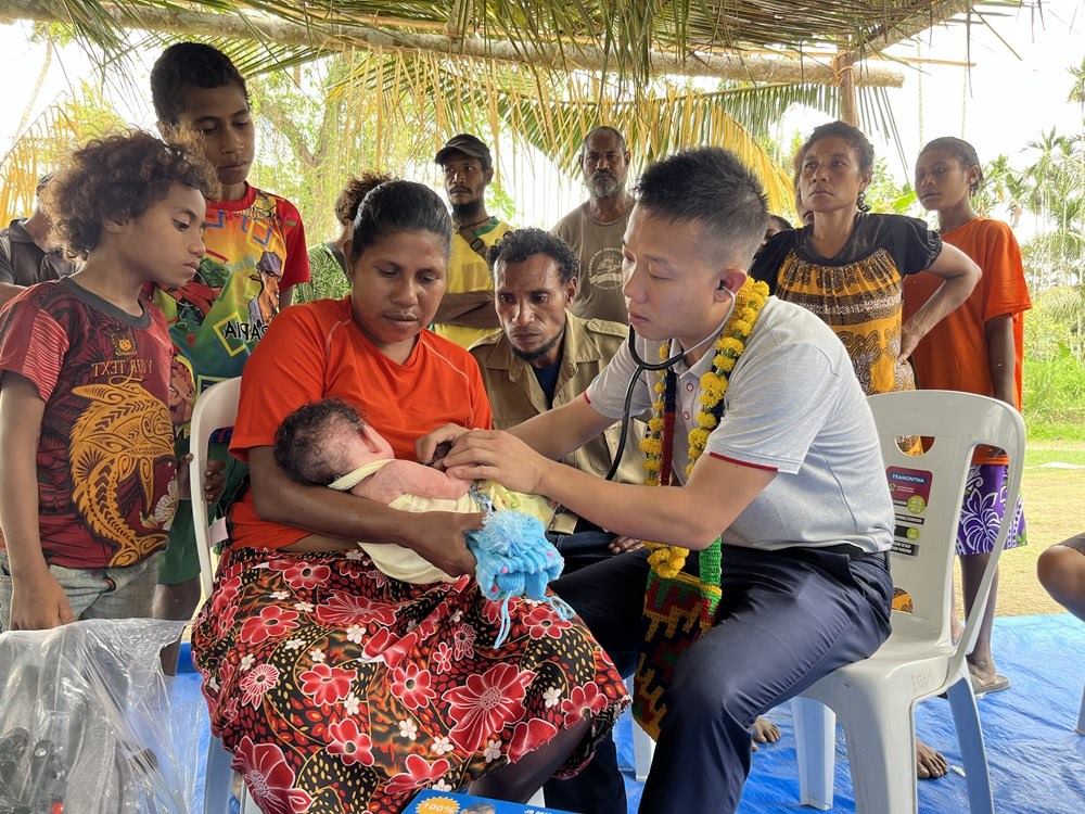 2023年8月5日，在巴布亞新幾內(nèi)亞中央省的一個(gè)村莊里，第12批援巴新中國(guó)醫(yī)療隊(duì)副隊(duì)長(zhǎng)、新生兒科副主任醫(yī)師劉振球?yàn)楫?dāng)?shù)貗雰郝?tīng)診檢查。新華社發(fā)（第12批援巴新中國(guó)醫(yī)療隊(duì)供圖）