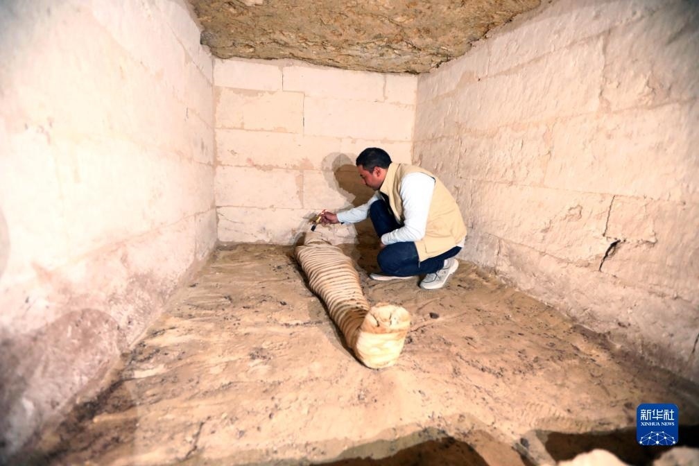 10月15日，在埃及明亞省考古現(xiàn)場，考古人員清理一座石鑿墓中的木乃伊。新華社發(fā)（艾哈邁德·戈馬攝）