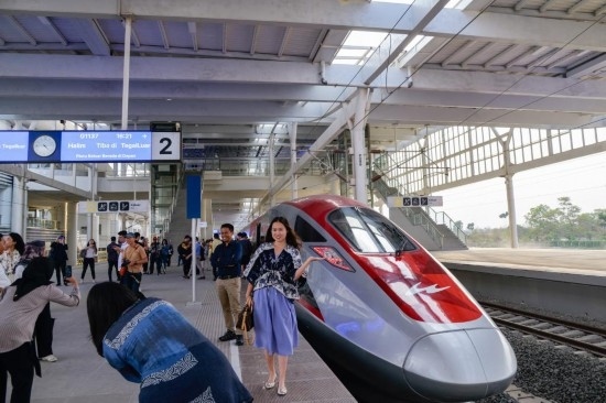  10月17日，在印度尼西亞萬隆德卡魯爾站，乘客在站臺上和雅萬高鐵高速動車組列車合影。新華社記者 徐欽 攝