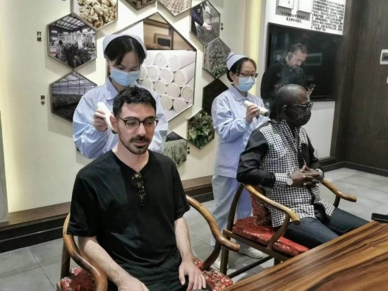 2023“一帶一路”媒體合作論壇聯(lián)合采訪團團員在九牛草展示館體驗艾灸。（本報記者 黃超攝）
