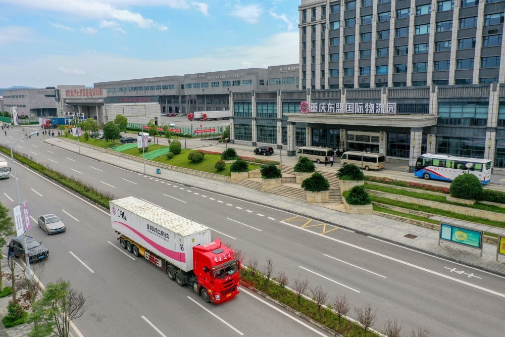 2023年10月11日，滿載筆記本電腦配件、發(fā)電機(jī)組件等產(chǎn)品的西部陸海新通道跨境公路班車從重慶南彭公路保稅物流中心駛出，將途經(jīng)廣西憑祥，直達(dá)越南（無人機(jī)照片）。新華社記者 黃偉 攝