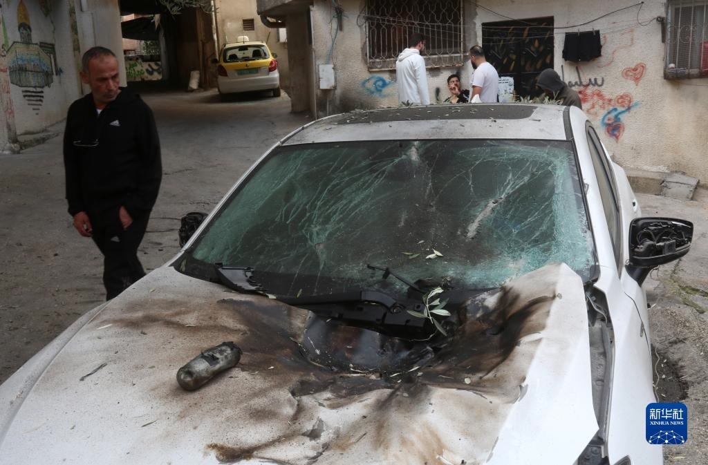 12月17日，在約旦河西岸城市圖勒凱爾姆附近的一處難民營，人們查看在沖突中損毀的車輛。新華社發(fā)（尼達(dá)爾·艾仕塔耶?dāng)z）