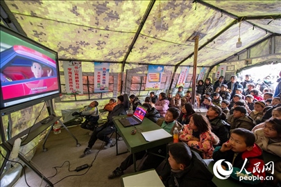 12月22日，在積石山縣大河家鎮(zhèn)大河村安置點，陸軍76集團(tuán)軍某旅搭建的“臨時學(xué)?！眱?nèi)，小朋友正在看動畫片。人民網(wǎng)記者 翁奇羽攝