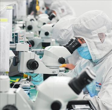 在位于武漢中國光谷的光電器件研發(fā)制造商——武漢光迅科技股份有限公司生產(chǎn)車間內(nèi)，技術(shù)人員在光模塊生產(chǎn)線作業(yè)（2023年4月11日攝）。程敏攝/本刊