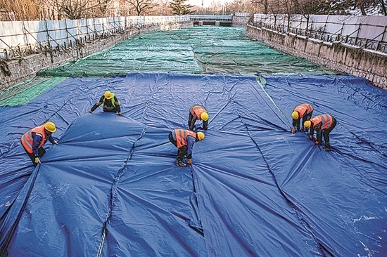 1月3日，房山區(qū)東風街道，工人正在修復的河道內給混凝土鋪設保溫布。