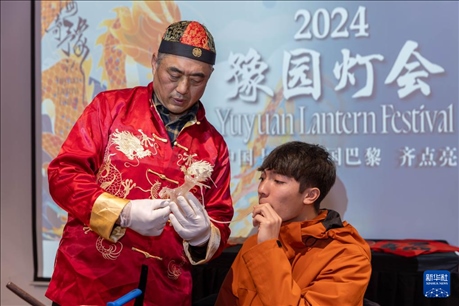 1月28日，在上海豫園舉行的民俗活動(dòng)上，美國(guó)馬斯卡廷中學(xué)學(xué)生在非遺傳承人的指導(dǎo)下吹糖偶。 新華社記者 王翔 攝