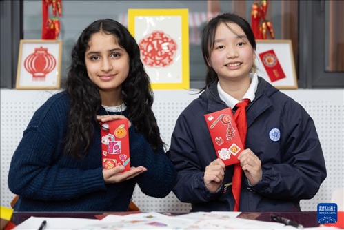 1月28日，美國(guó)馬斯卡廷中學(xué)學(xué)生（左）和復(fù)旦大學(xué)第二附屬學(xué)校學(xué)生展示互相送出的寫(xiě)有寄語(yǔ)祝福的紅包。 新華社記者 王翔 攝