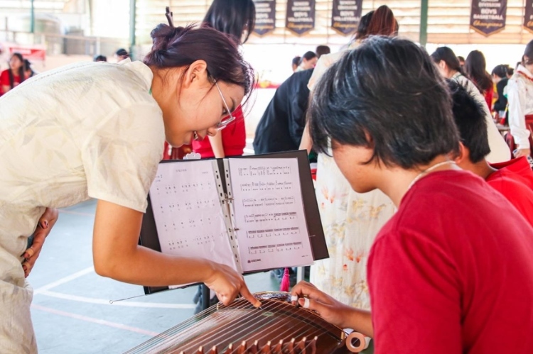 志愿者教師指導學生彈奏古箏?；顒又鬓k方供圖