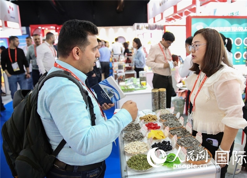 圖為一家中國(guó)干果參展企業(yè)代表與采購(gòu)商洽談。人民網(wǎng) 塔里克·易卜拉欣攝