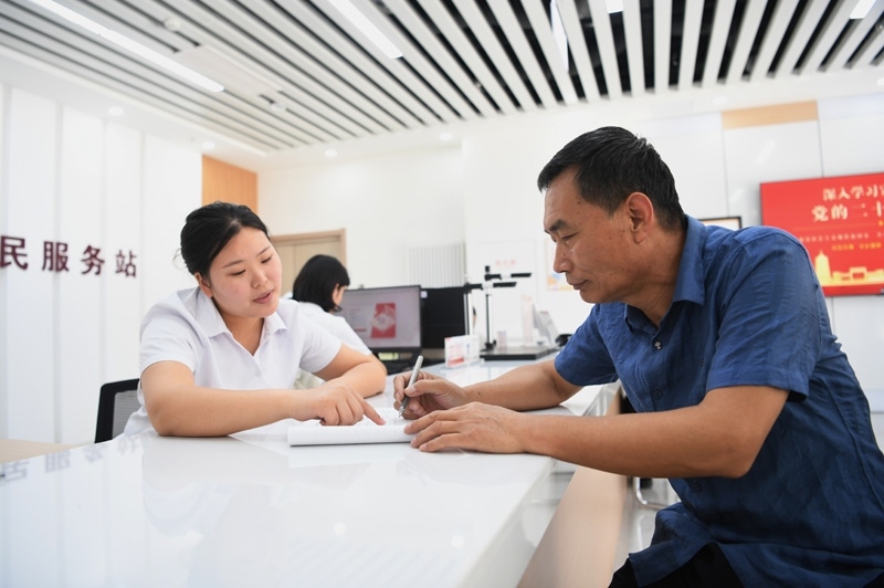 2023年5月23日，河北雄安新區(qū)容東片區(qū)南文營(yíng)社區(qū)居民（右）在社區(qū)便民服務(wù)站辦理業(yè)務(wù)。