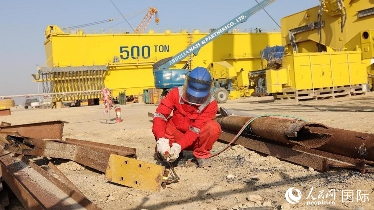 工人正在龍門吊吊裝現(xiàn)場切割金屬件。人民網(wǎng)記者管克江攝