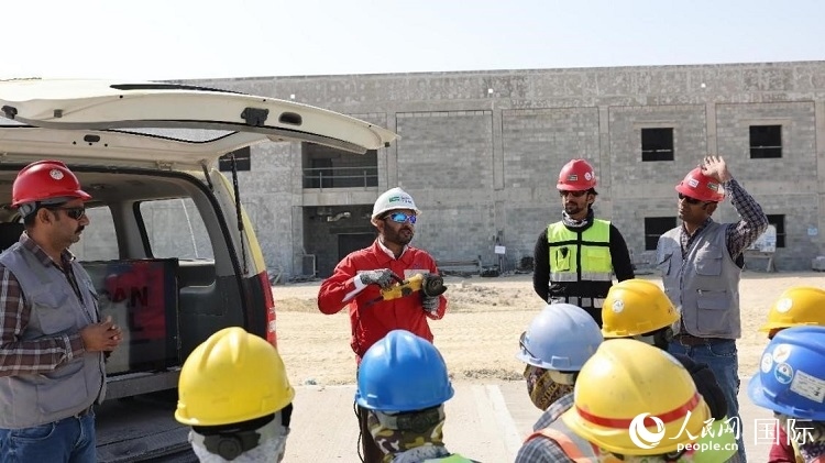 穆薩瓦爾(圖中紅衣人）現(xiàn)場演示工具操作規(guī)范。人民網(wǎng)記者 管克江攝