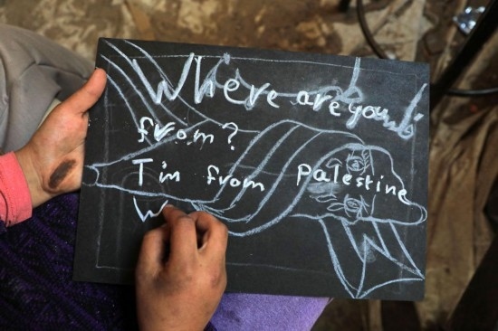 2023年12月28日，一名學(xué)生在加沙地帶南部城市拉法一所學(xué)校的臨時(shí)教室中寫(xiě)下“我來(lái)自巴勒斯坦”的字樣。新華社發(fā)（里澤克·阿卜杜勒賈瓦德攝）