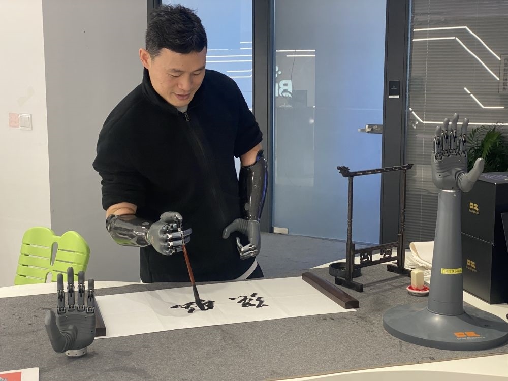 2024年3月29日，在浙江強(qiáng)腦科技有限公司展廳內(nèi)，失去雙手的產(chǎn)品體驗(yàn)官倪敏成依靠智能仿生手寫毛筆字。新華社記者 魏一駿 攝