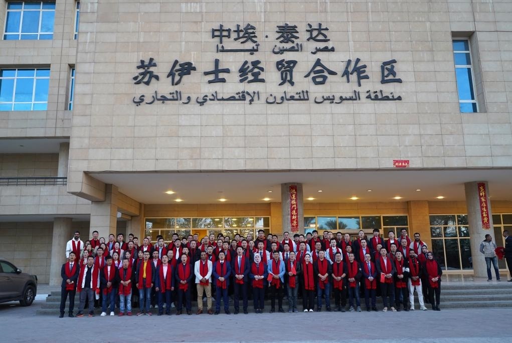 2024年2月11日，在位于埃及蘇伊士省的中?！ぬ┻_(dá)蘇伊士經(jīng)貿(mào)合作區(qū)，中埃員工在合作區(qū)辦公大樓前合影拜年。新華社發(fā)（泰達(dá)合作區(qū)供圖）