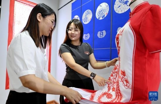 5月31日，在衡水市阜城縣一家剪紙工作室，游客在觀賞帶有剪紙?jiān)氐钠炫邸? width=