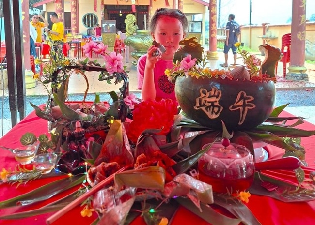 小朋友展示學(xué)裹粽子的成品照。組委會供圖