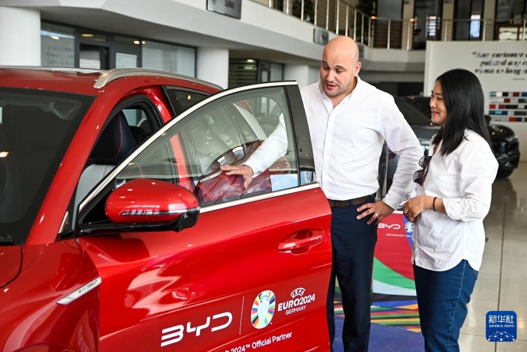 2024年5月29日，在馬耳他比爾基卡拉，馬耳他哈桑-扎米特汽車公司首席執(zhí)行官德古阿拉（左）介紹一輛比亞迪純電動汽車。新華社發(fā)（喬納森·博格 攝）