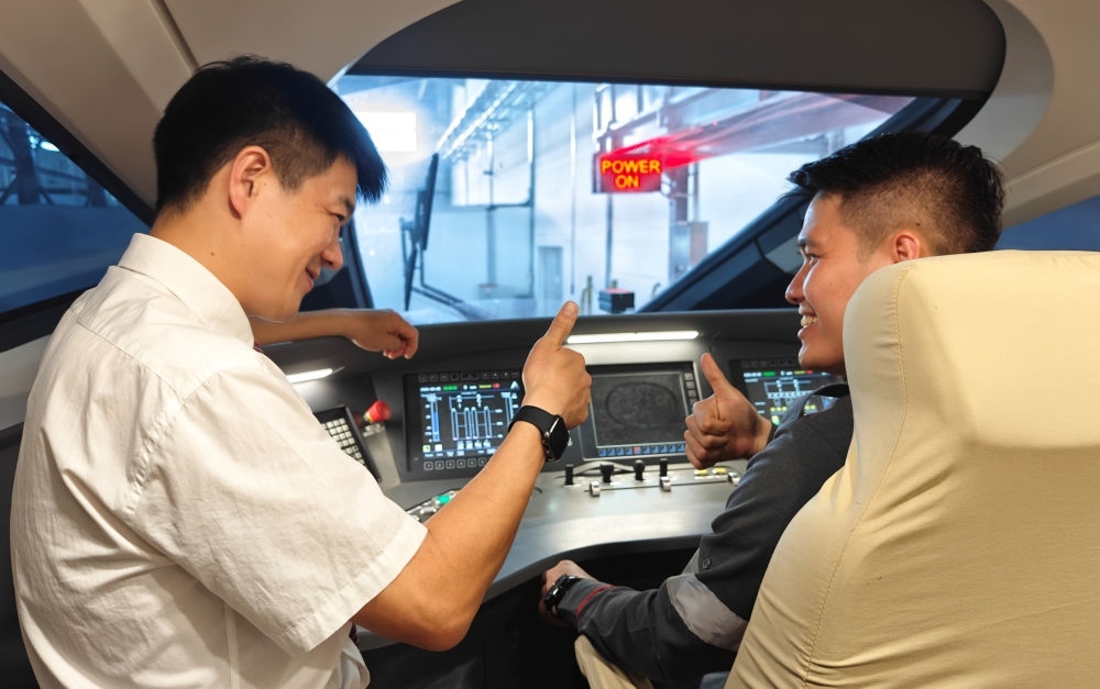 2023年8月25日，在印度尼西亞萬隆的雅萬高鐵德卡魯爾動車所內(nèi)，中國師傅穆振（左）向印尼火車司機(jī)塞蒂亞萬講解動車組出庫前的上電作業(yè)。新華社記者 徐欽 攝