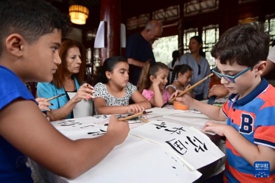 7月4日，在馬耳他桑塔露琪亞市的中國古典園林“靜園”，人們體驗(yàn)中國書法。新華社發(fā)（喬納森·博格 攝）