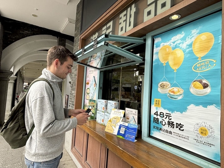 來自德國的留學(xué)生理查德在杭州西湖邊一家商鋪使用支付寶掃碼支付（2024年4月11日攝）。新華社發(fā)