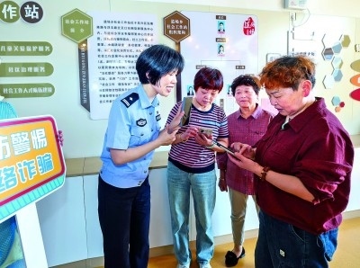 浙江湖州民警指導居民加入湖州“e企安”微信群，實時接收反詐信息。新華社發(fā)