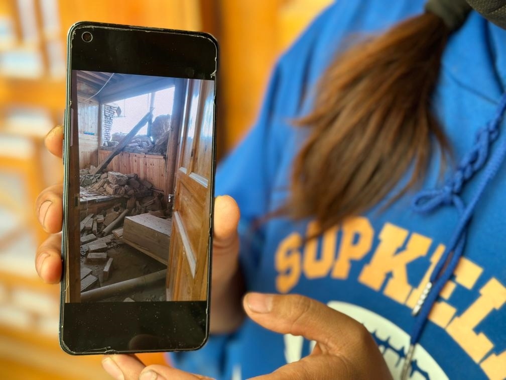 圖為7月17日拉毛東智在手機上找出地震后房屋受損的照片。新華社記者 張子琪 攝