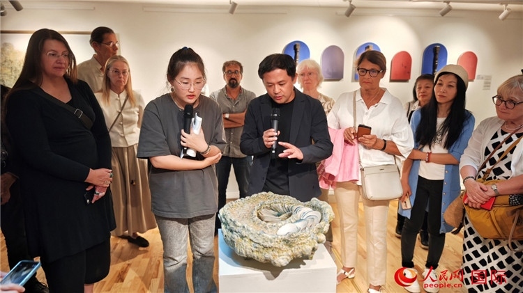 參展人、景德鎮(zhèn)陶瓷大學(xué)設(shè)計(jì)藝術(shù)學(xué)院副院長(zhǎng)余劍峰（中）向來(lái)賓介紹參展作品。人民網(wǎng)記者 殷淼攝
