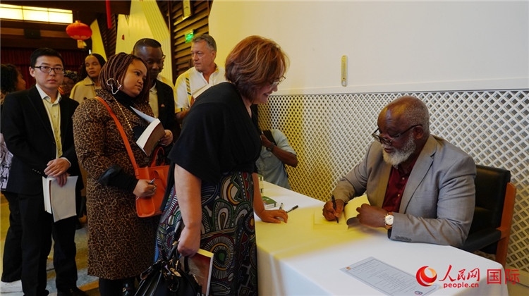 譚哲理在活動現(xiàn)場簽名贈書。人民網(wǎng) 劉暢攝