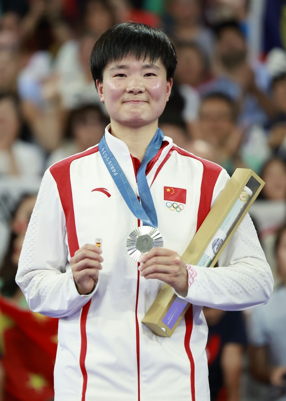 巴黎奧運(yùn)會(huì)羽毛球女子單打亞軍、中國(guó)選手何冰嬌在頒獎(jiǎng)儀式上一手握著銀牌，一手握著西班牙奧委會(huì)徽章（2024年8月5日攝）。新華社記者 任正來(lái) 攝