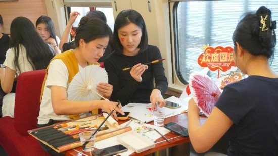 10月1日，旅客們?cè)贕1634次列車上給油紙傘作畫。新華社記者周義 攝