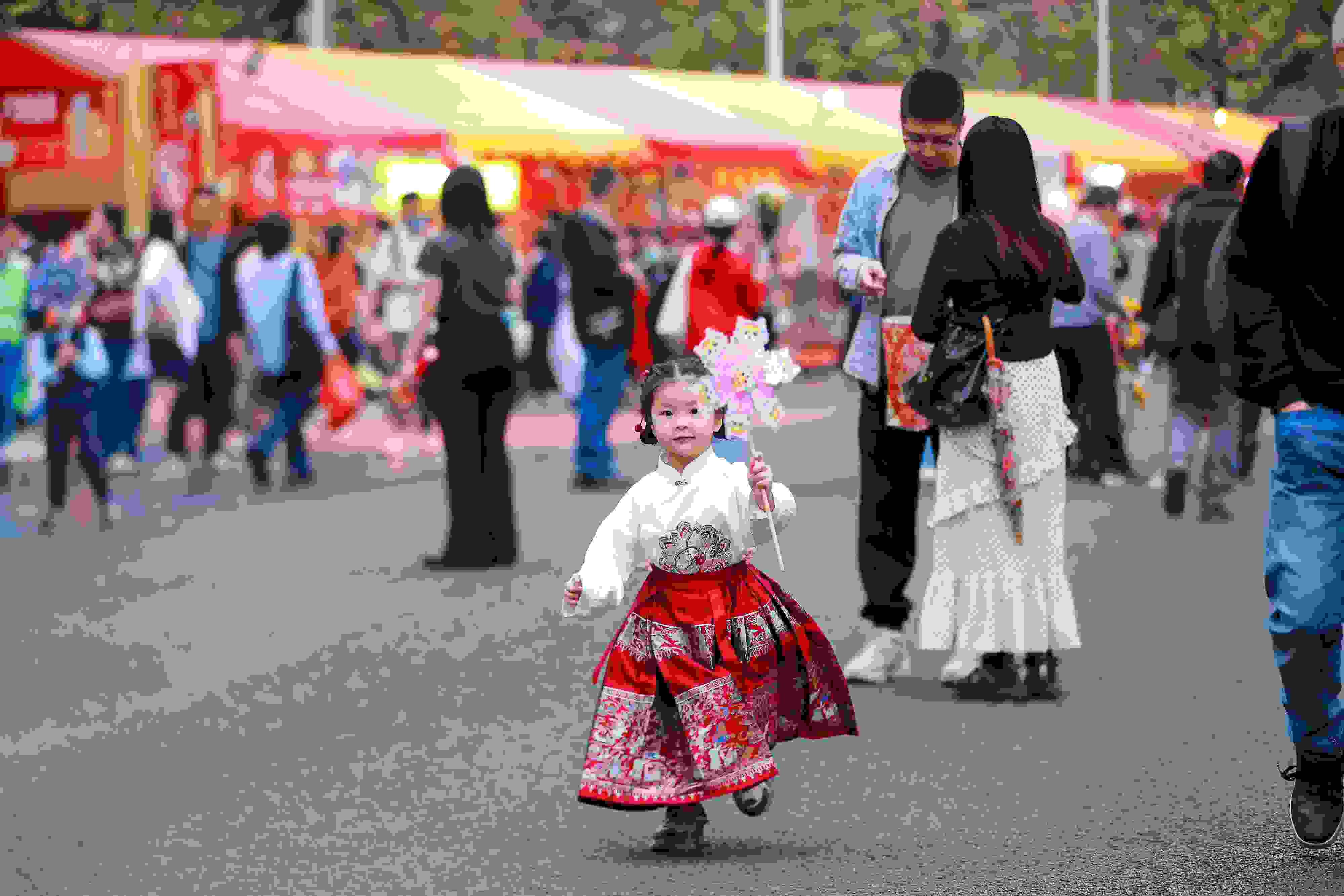 拿著風(fēng)車穿著馬面裙的小女孩在廣州的花市上開心奔跑。