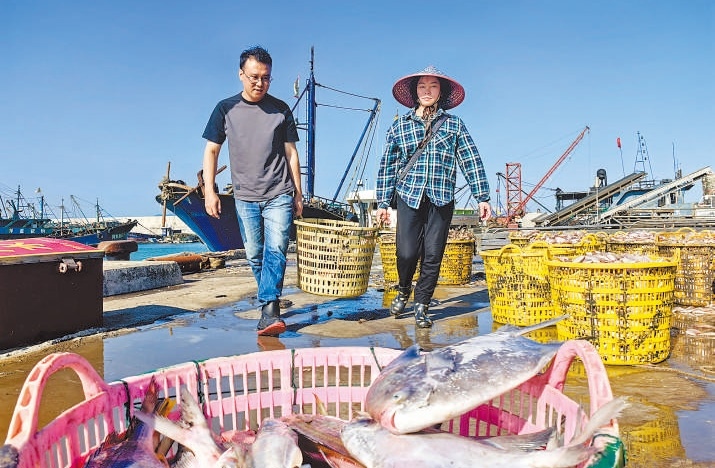 許小斌（左）和漁民一起搬運(yùn)海鮮。本報(bào)記者 付 文攝