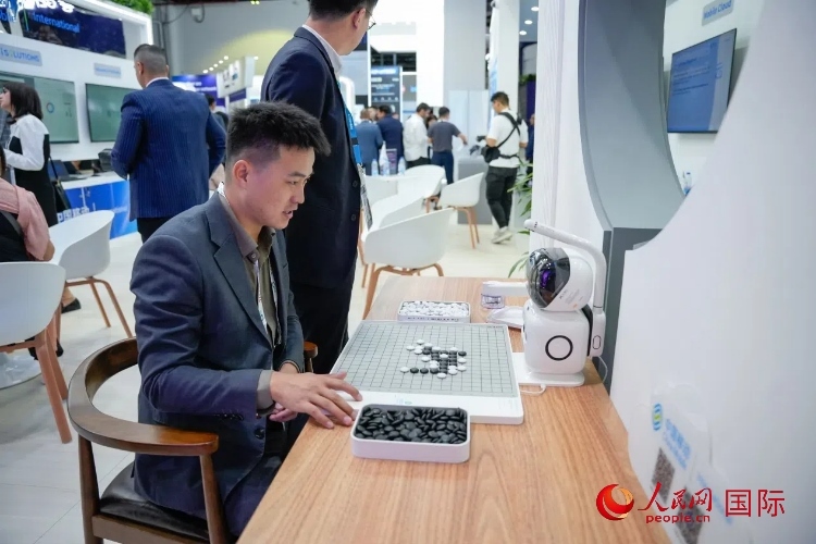 觀眾在中國移動(dòng)國際有限公司展臺(tái)體驗(yàn)智慧圍棋機(jī)器人。人民網(wǎng) 塔里克·易卜拉欣攝