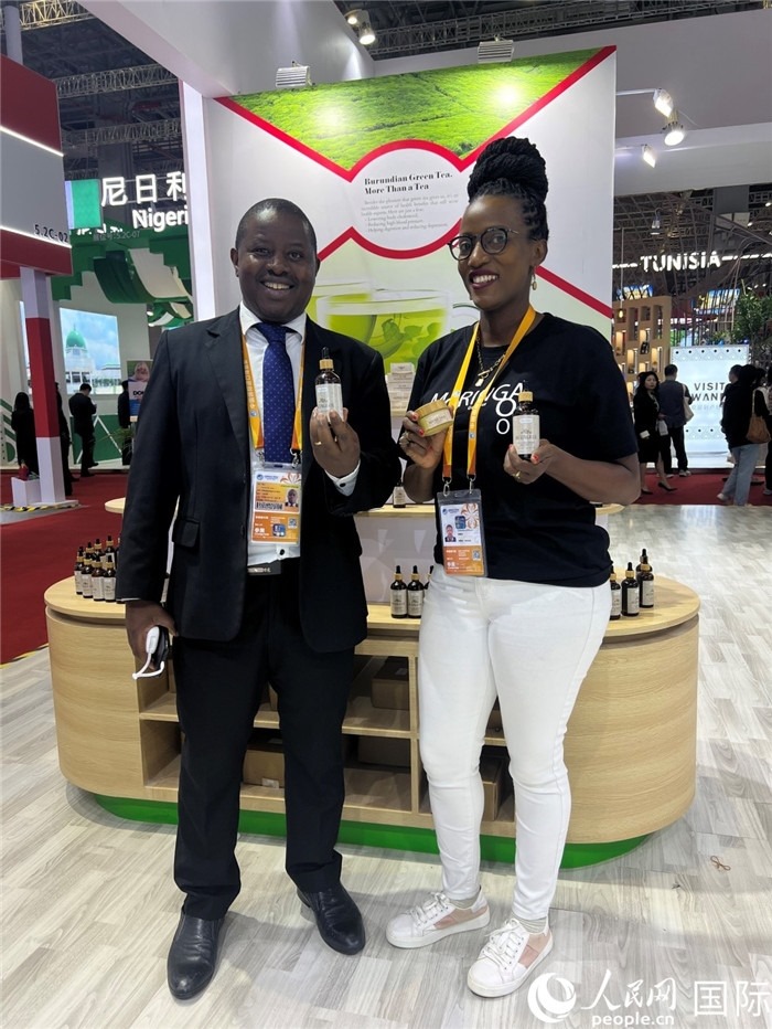 6月6日，布隆迪駐華大使館一等參贊布利馬索·阿爾弗雷德 (左，Bulimaso Alfred) 和參展商卡馬里扎·埃斯特拉 (Kamariza Estella) 在第七屆中國(guó)國(guó)際進(jìn)口博覽會(huì)布隆迪館展示當(dāng)?shù)厣a(chǎn)的辣木油。（人民網(wǎng) 艾里士 攝）