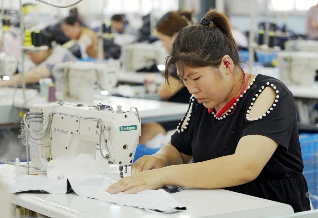 5月20日，村民在李寨村服裝加工廠內(nèi)忙碌。河南省周口市沈丘縣馮營(yíng)鎮(zhèn)李寨村地處豫東平原。近年來，乘著脫貧攻堅(jiān)與鄉(xiāng)村振興政策的東風(fēng)，李寨村積極探索產(chǎn)業(yè)發(fā)展模式，通過“龍頭企業(yè)+村集體經(jīng)濟(jì)+農(nóng)戶”的方式，逐漸發(fā)展形成肉牛養(yǎng)殖、設(shè)施農(nóng)業(yè)、服裝加工、康養(yǎng)民宿等產(chǎn)業(yè)，以產(chǎn)業(yè)振興助力鄉(xiāng)村振興。新華社記者 李嘉南 攝