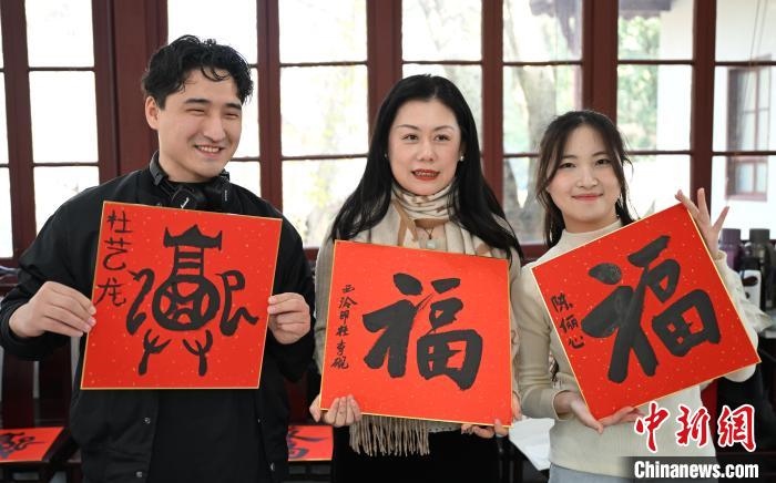 1月20日，外籍留學(xué)生和西泠印社社員李硯(中)展示各自創(chuàng)作的福貼。當(dāng)日，來自巴西、馬來西亞、加納、哈薩克斯坦的外籍留學(xué)生在浙江杭州西泠印社體驗(yàn)福貼、春聯(lián)和篆刻，感受古老的中國傳統(tǒng)文化。中新社記者 王剛 攝