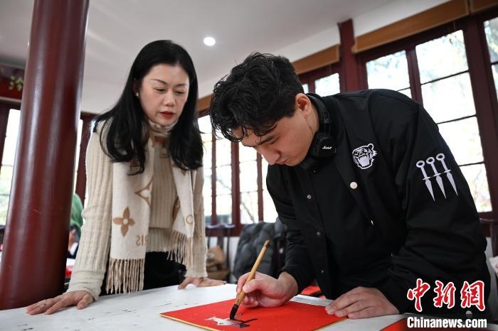 1月20日，外籍留學(xué)生在西泠印社社員李硯指導(dǎo)下寫福。當(dāng)日，來自巴西、馬來西亞、加納、哈薩克斯坦的外籍留學(xué)生在浙江杭州西泠印社體驗(yàn)福貼、春聯(lián)和篆刻，感受古老的中國傳統(tǒng)文化。中新社記者 王剛 攝