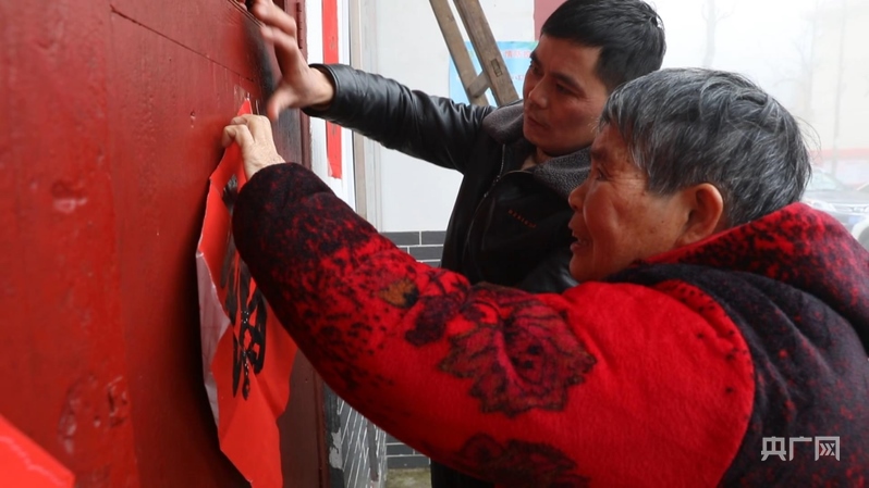 彭德良與70多歲母親貼春聯(lián)（央廣網記者 郇康新 攝）